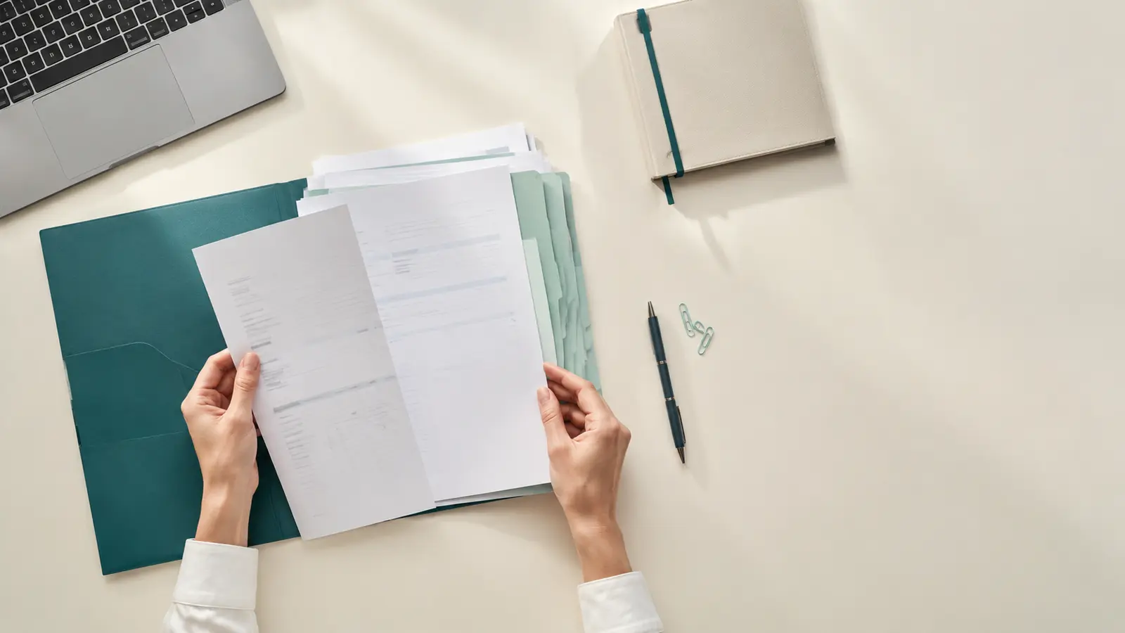Manos organizando documentación sobre un escritorio
